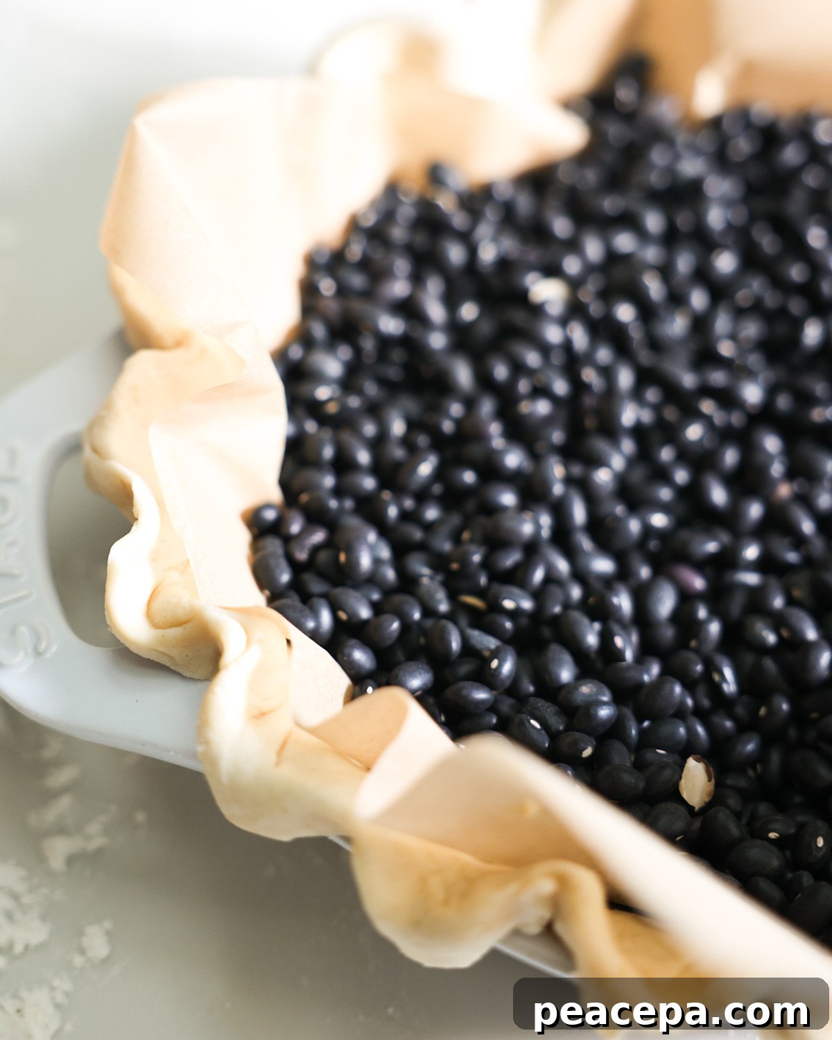 beans and parchment paper in a vegan pie crust to blind bake