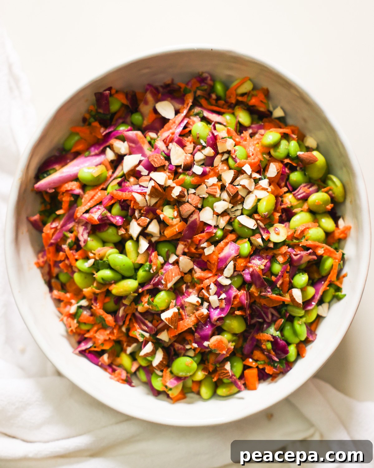 An overhead shot of a bowl of edamame salad garnished with chopped almonds.