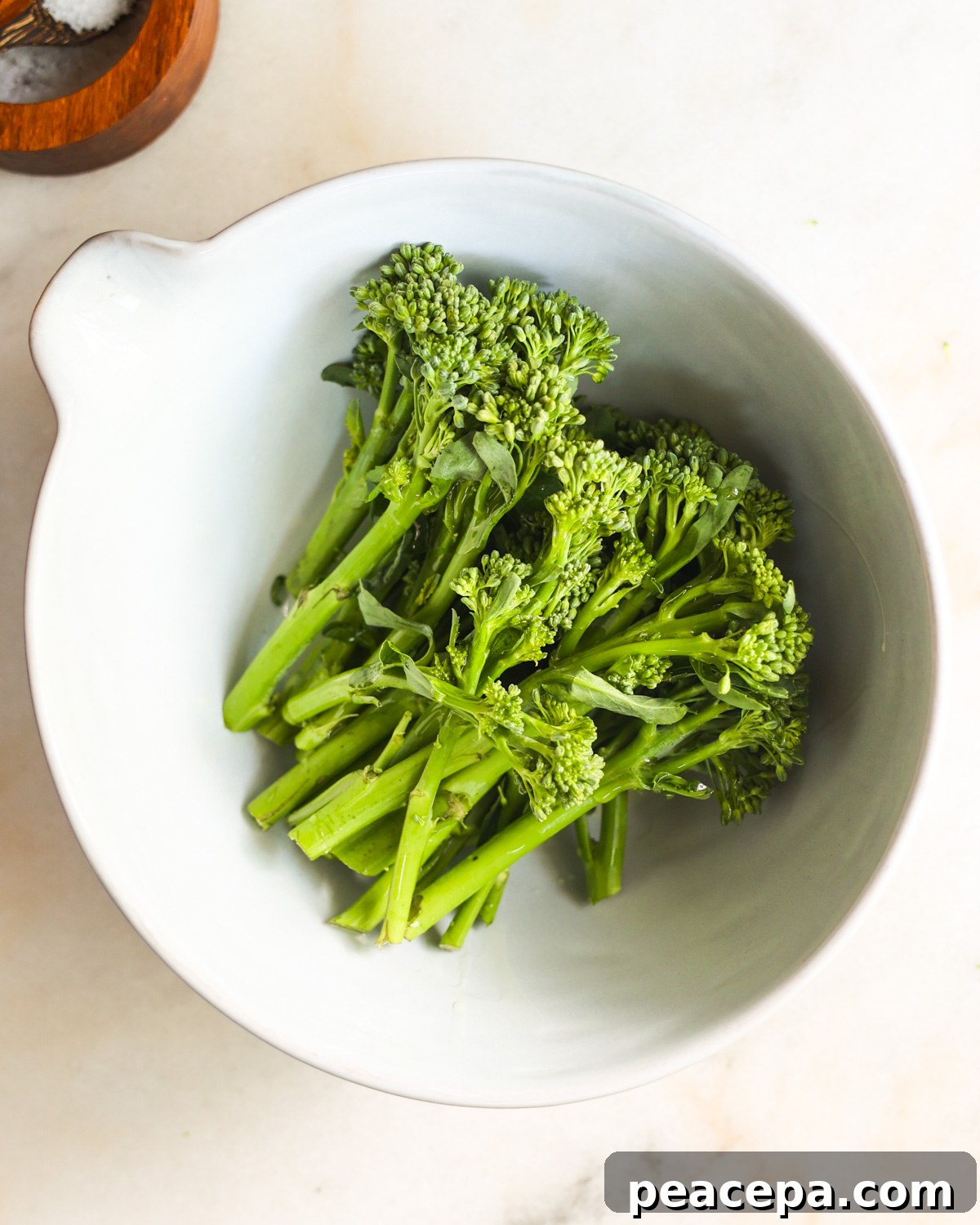 An overhead shot of the air fryer broccolini in a white mixing bowl.