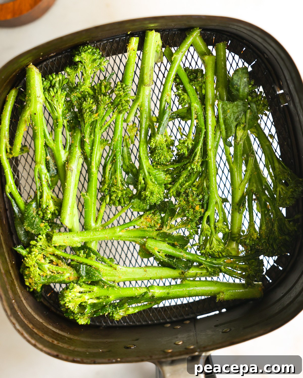 The seasoned broccolini in the air fryer basket.