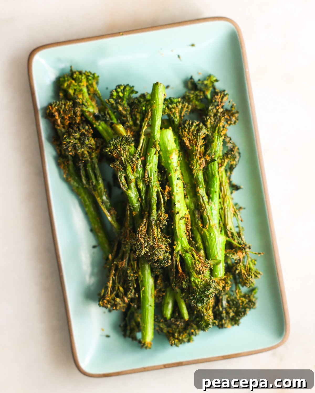 Air fryer broccolini on a small serving plate.
