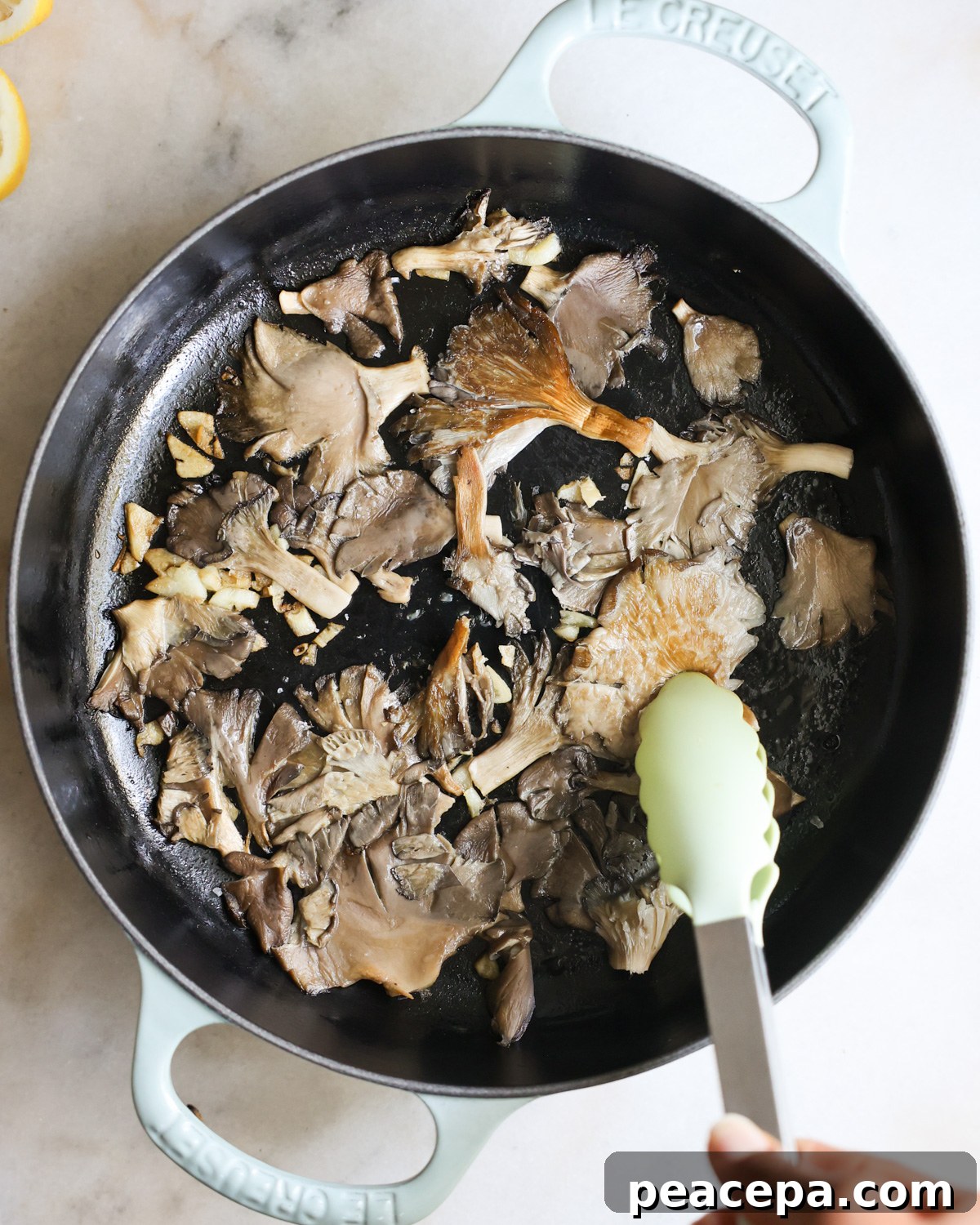 flipping pan-fried oyster mushrooms with tongs