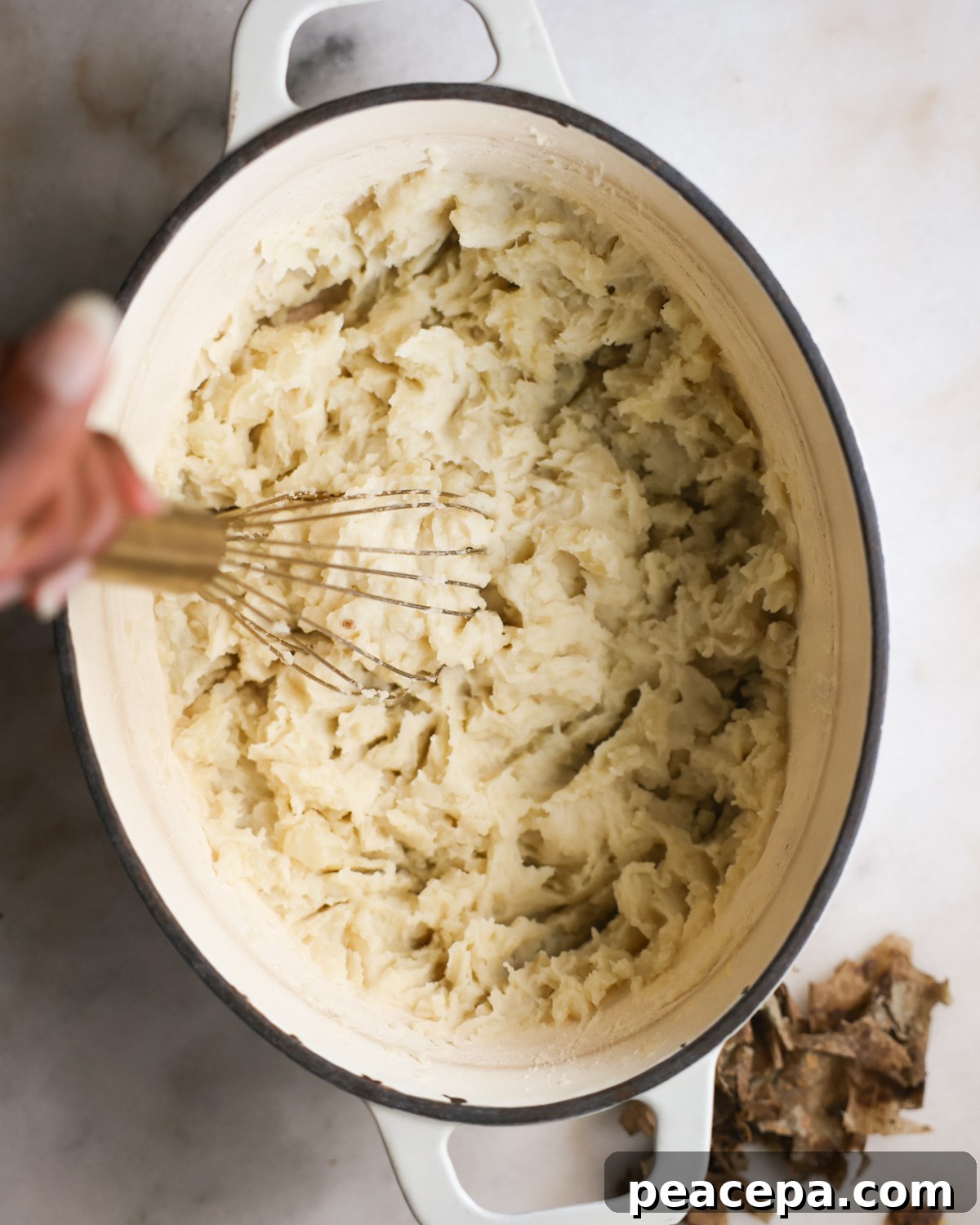 overhead of a whisk mashing vegan mashed potatoes