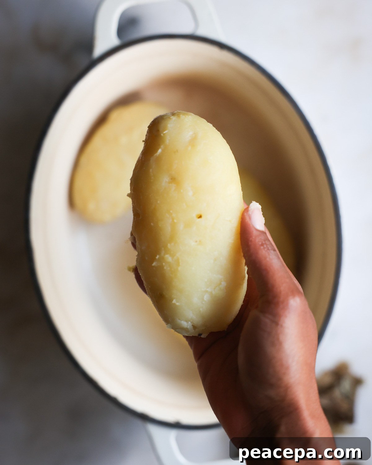 overhead of a peeled potato in a hand