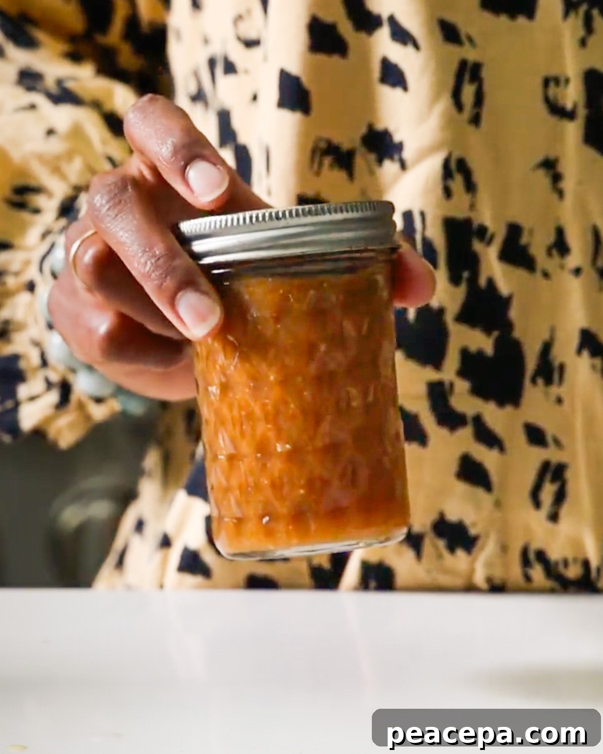 hand shaking pomegranate vinaigrette in a jar