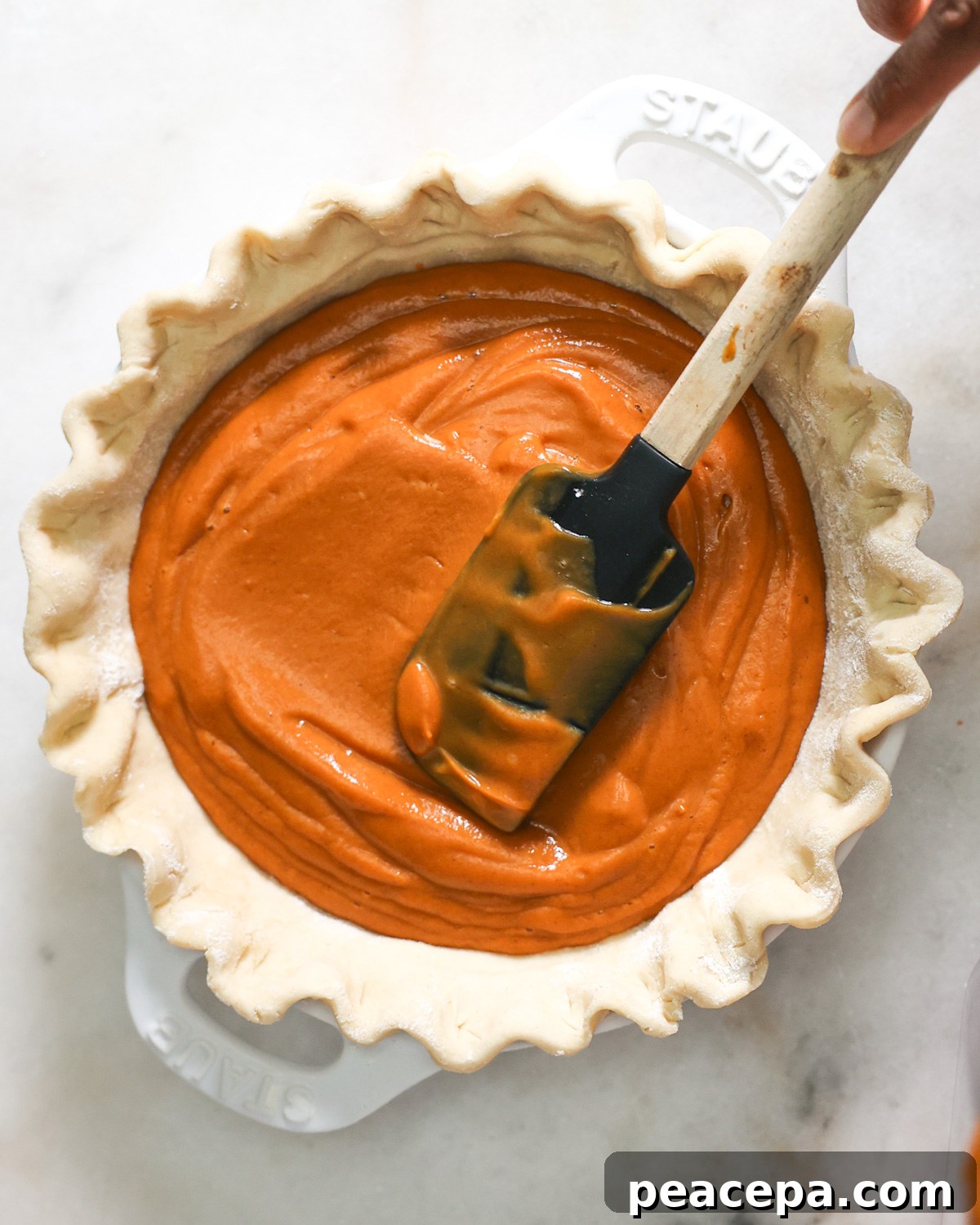 overhead of spatula spreading sweet potato filling in pie