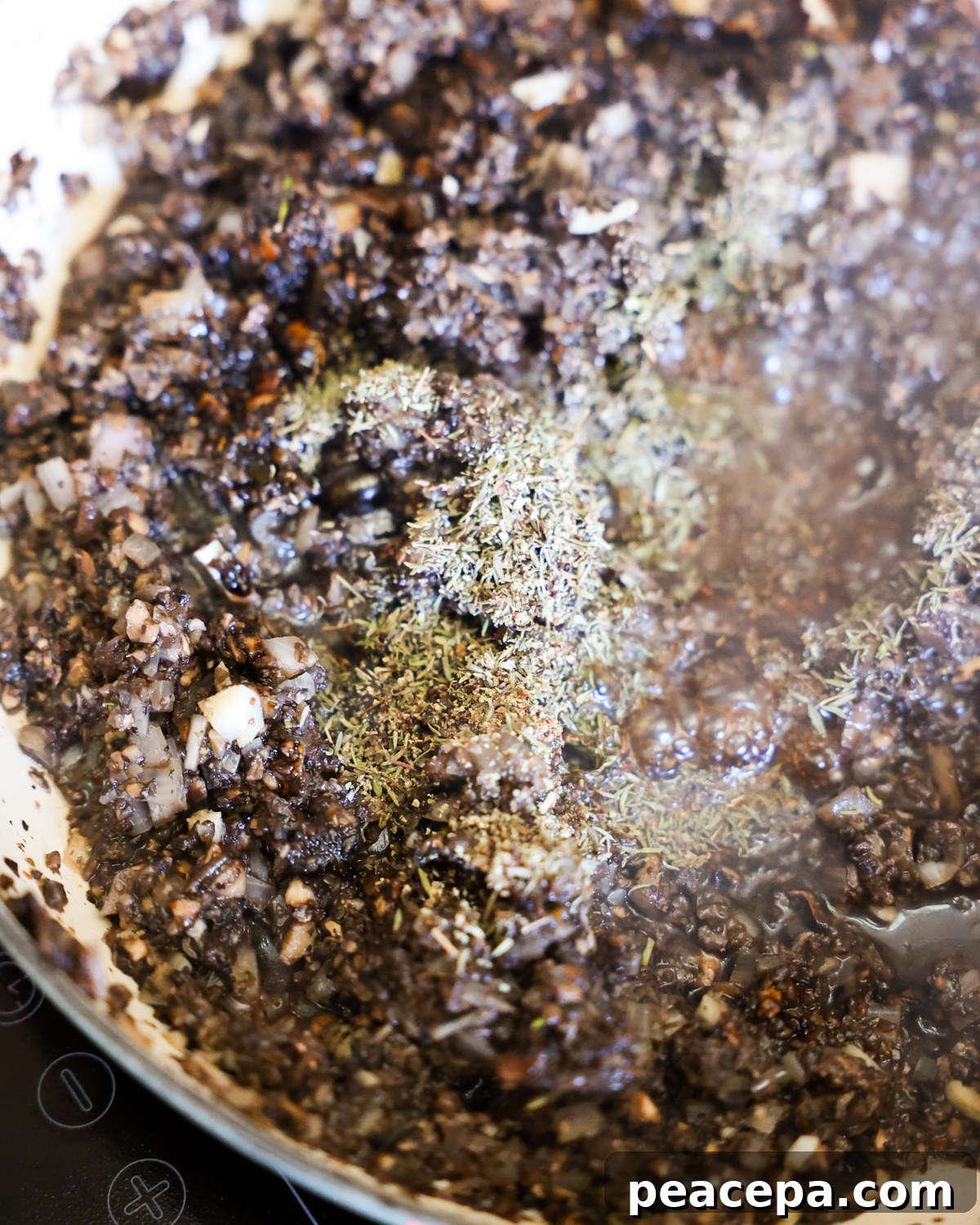 A close-up shot of the chopped onions cooking in a pan with herbs.