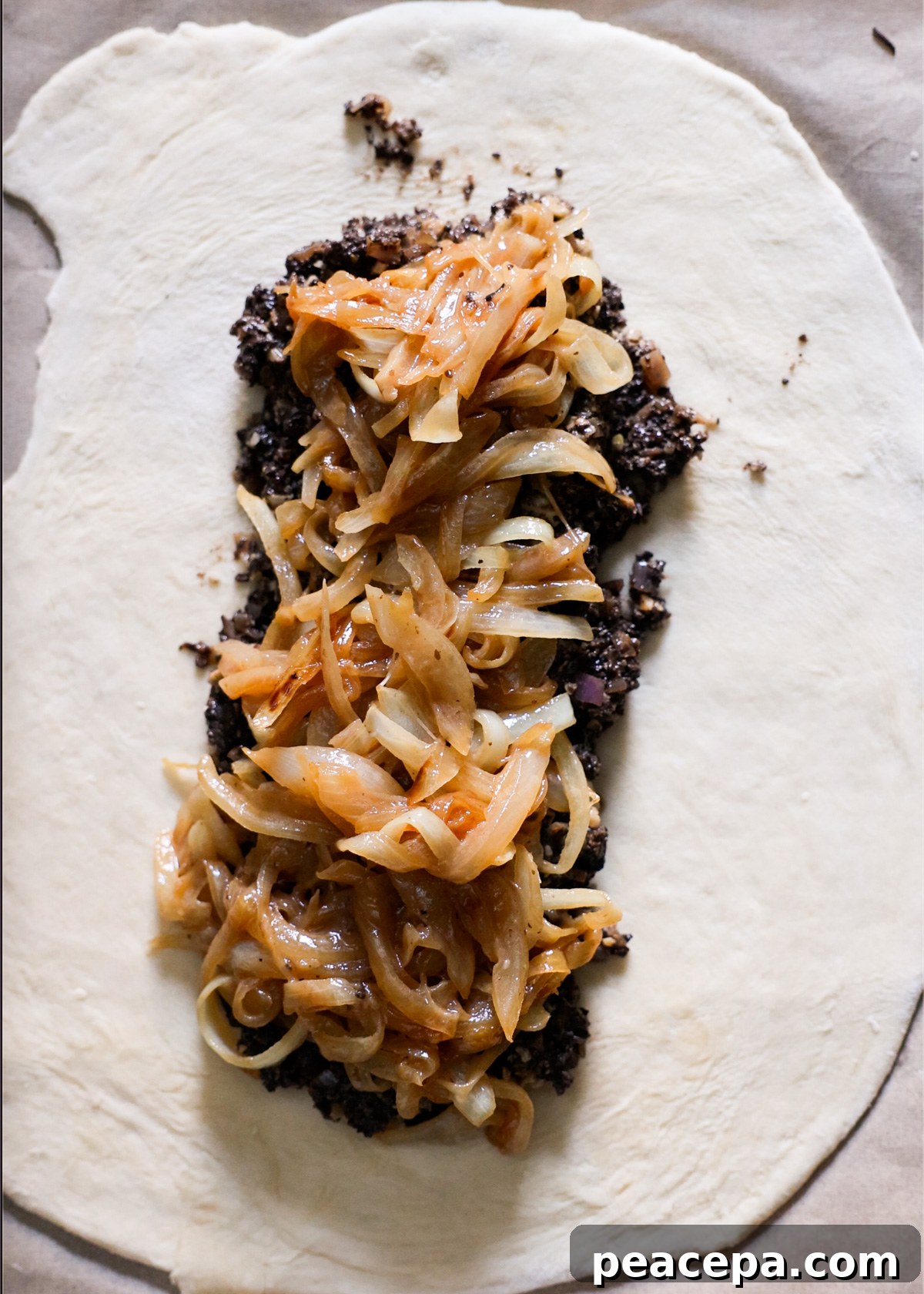 Layering the caramelized onions and mushroom mixture on the rolled out pastry.