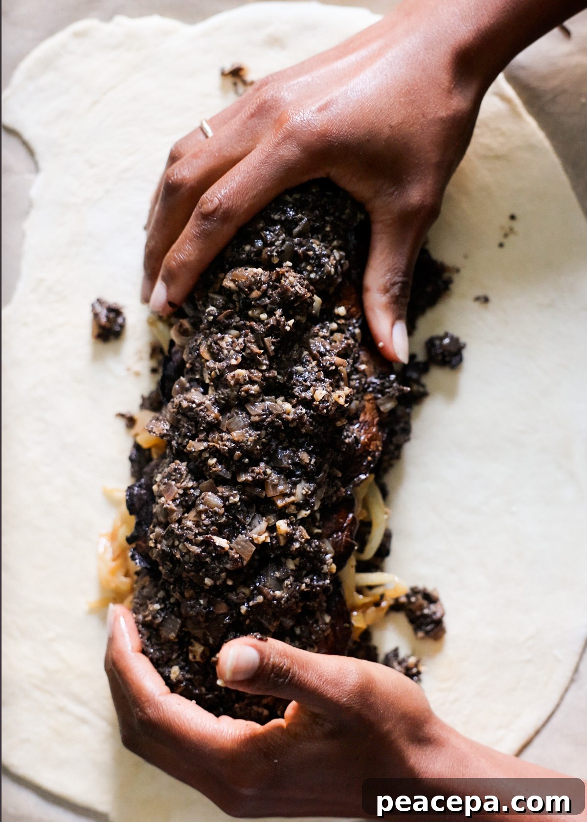 Two brown hands ently forming the vegetable fillings into a compact loaf shape.