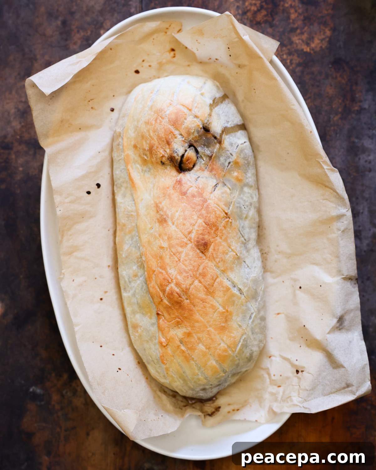 An overhead shot of the baked Wellington on a parchment-lined serving platter.