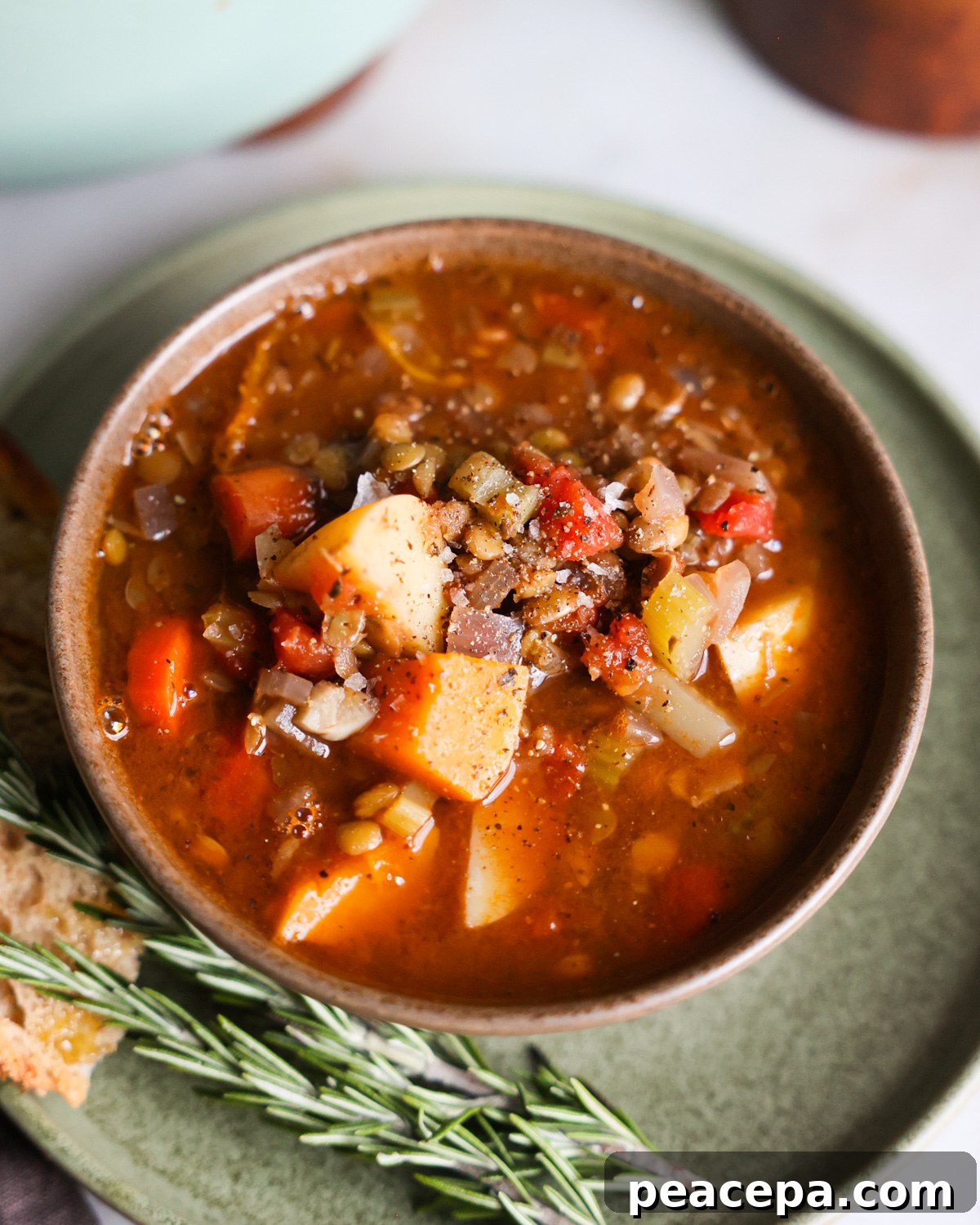 A close-up angled overhead shot of a small brown bowl of the butternut squash lentil soup.