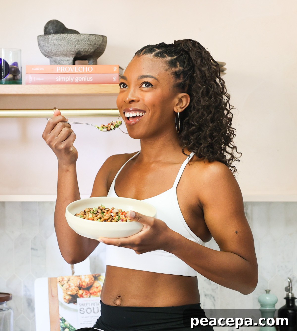 Black woman in kitchen holding salad