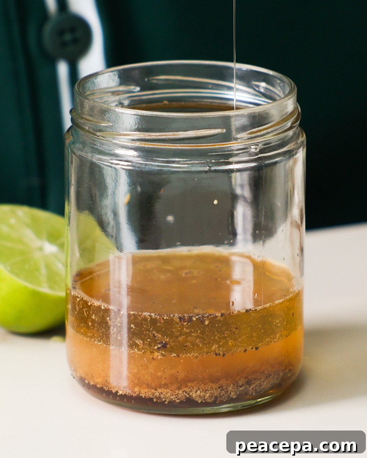 Adding the black bean and corn dressing ingredients to a glass jar.