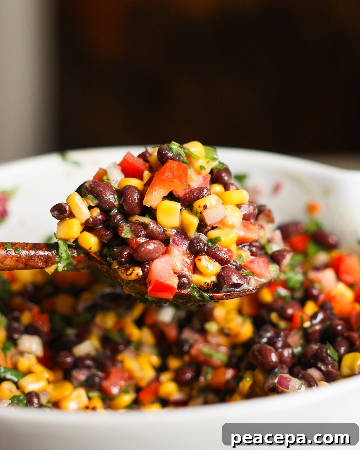 A close up shot of a spoonful of black bean and corn salad.
