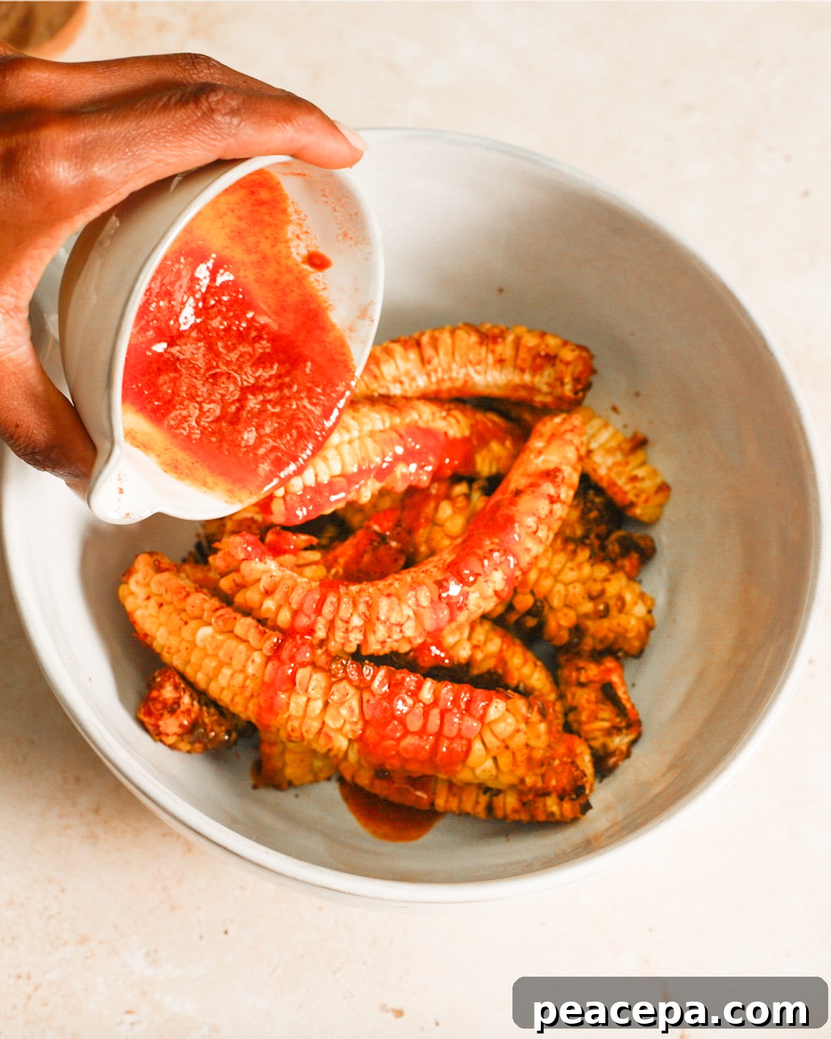 overhead pouring buttery spices on corn