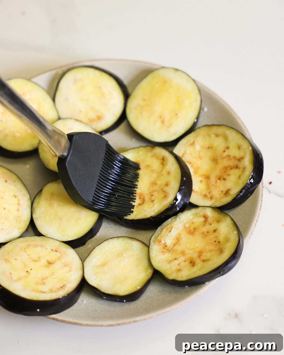 brushing oil on eggplant slices on plate