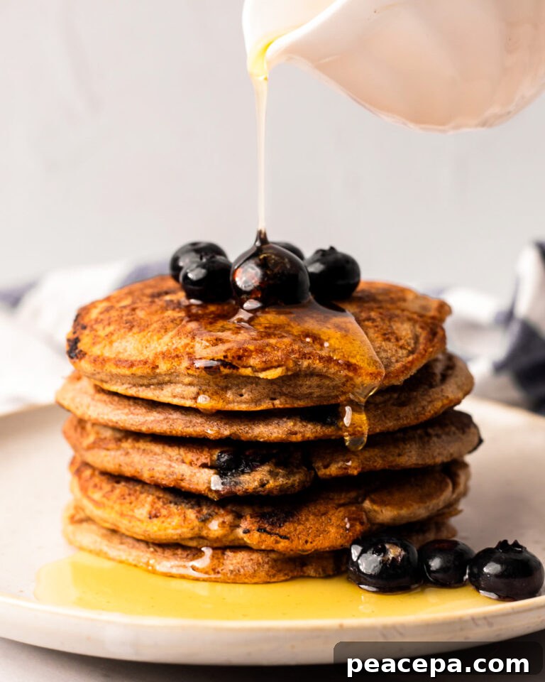 Drizzling a stack of the vegan blueberry pancakes with maple syrup.