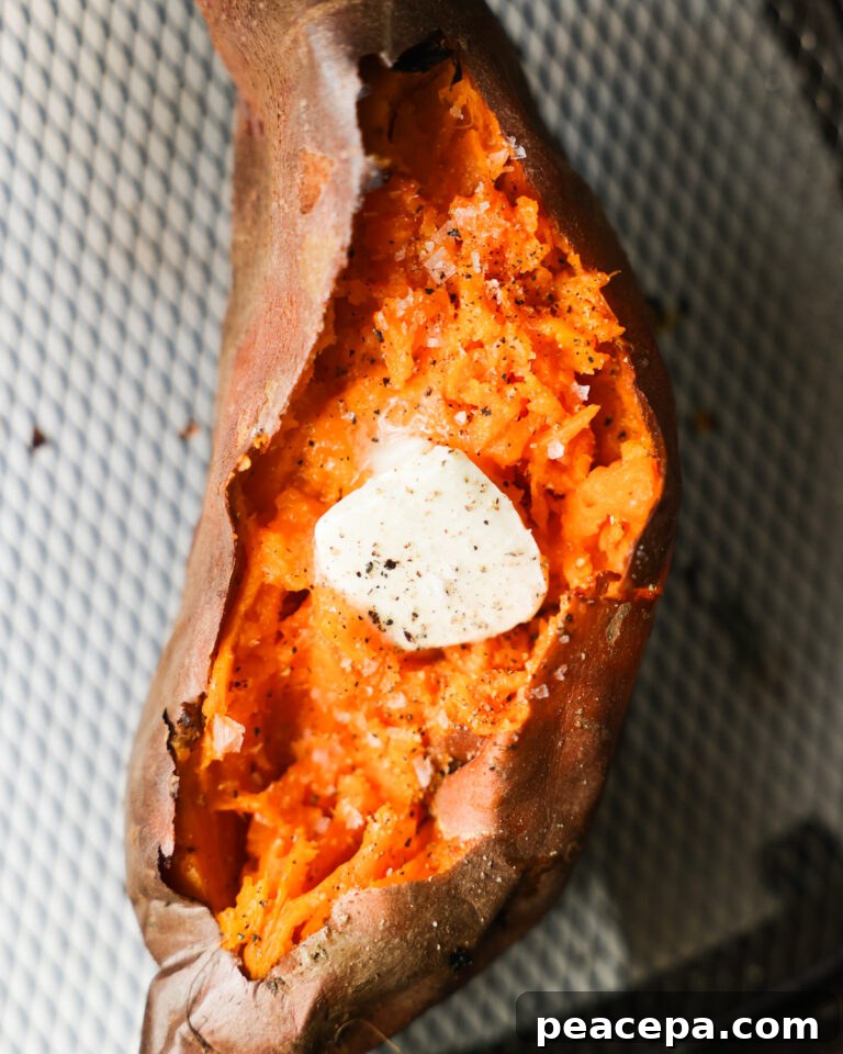 An overhead shot of an air fryer sweet potato, cut open and topped with butter, salt, and pepper.