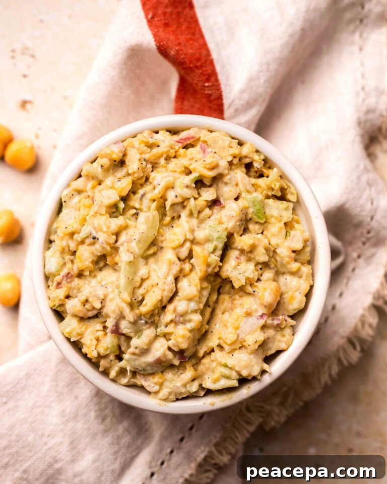 An overhead shot of a white bowl of tuna chickpea salad on a dish towel.