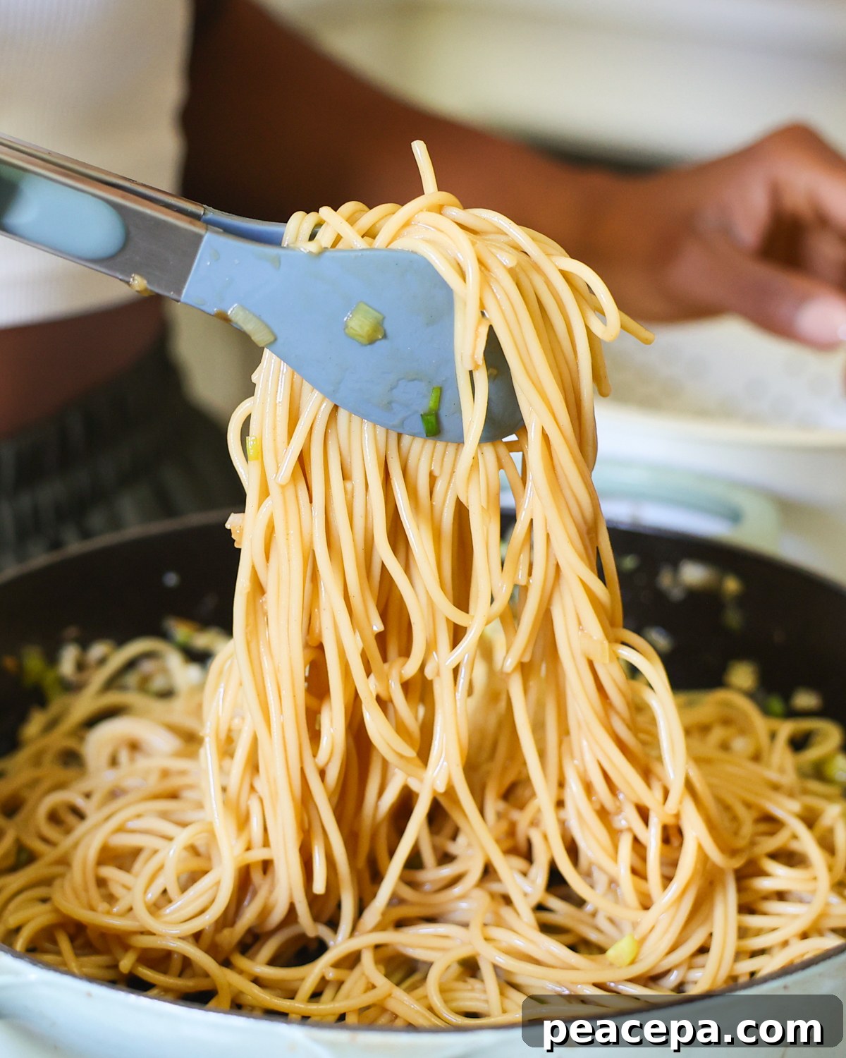 tossing noodles in sauce