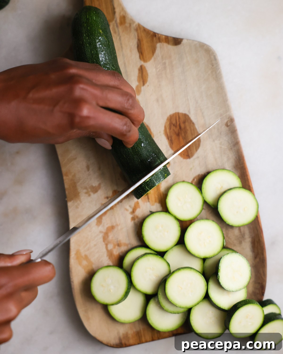 Slicing a zucchini on a cutting board.