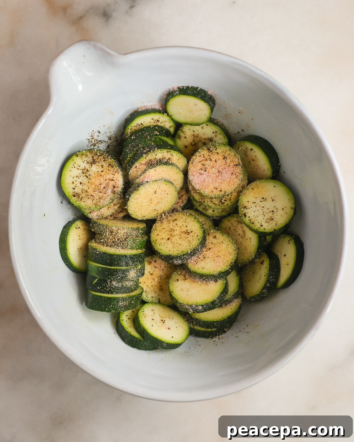 A bowl of zucchini sprinkled with seasonings.