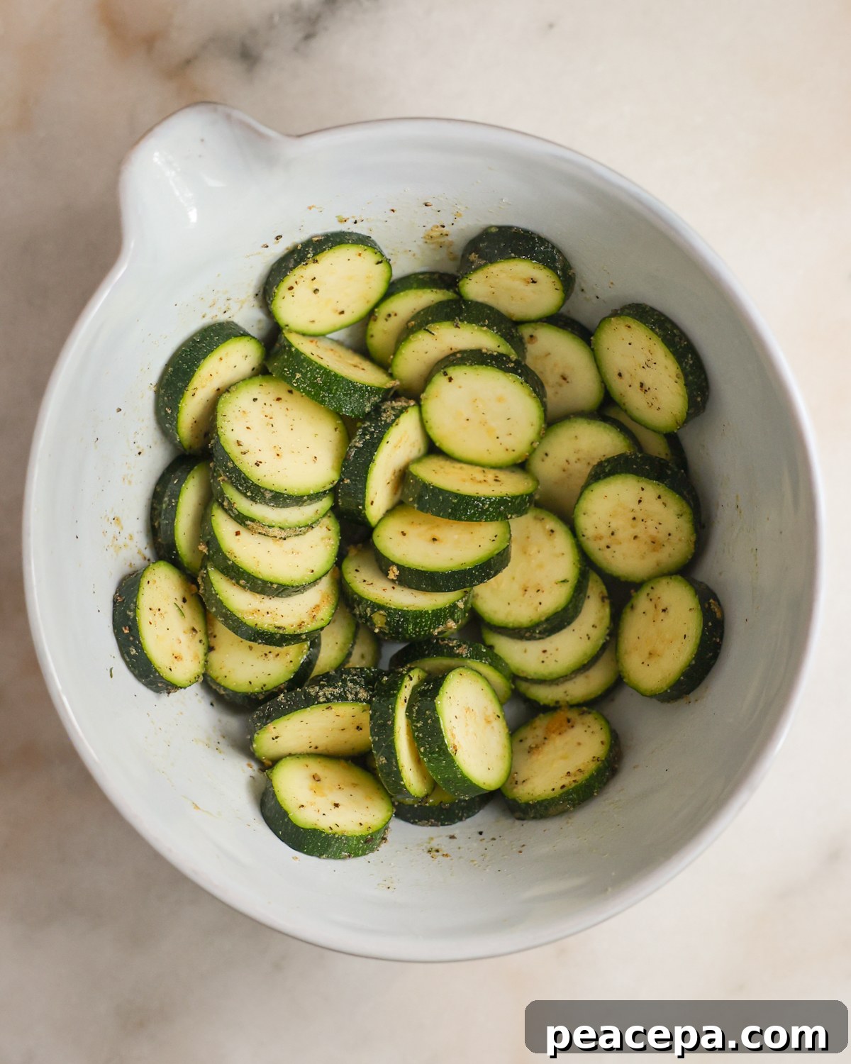 A bowl of sliced, seasoned zucchini.