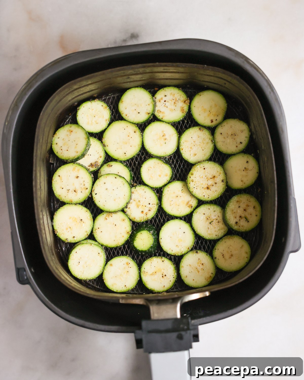 Sliced zucchini in an air fryer basket.