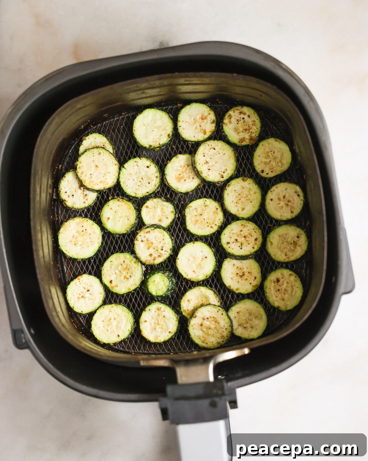 Cooked air fryer zucchini in an air fryer basket.