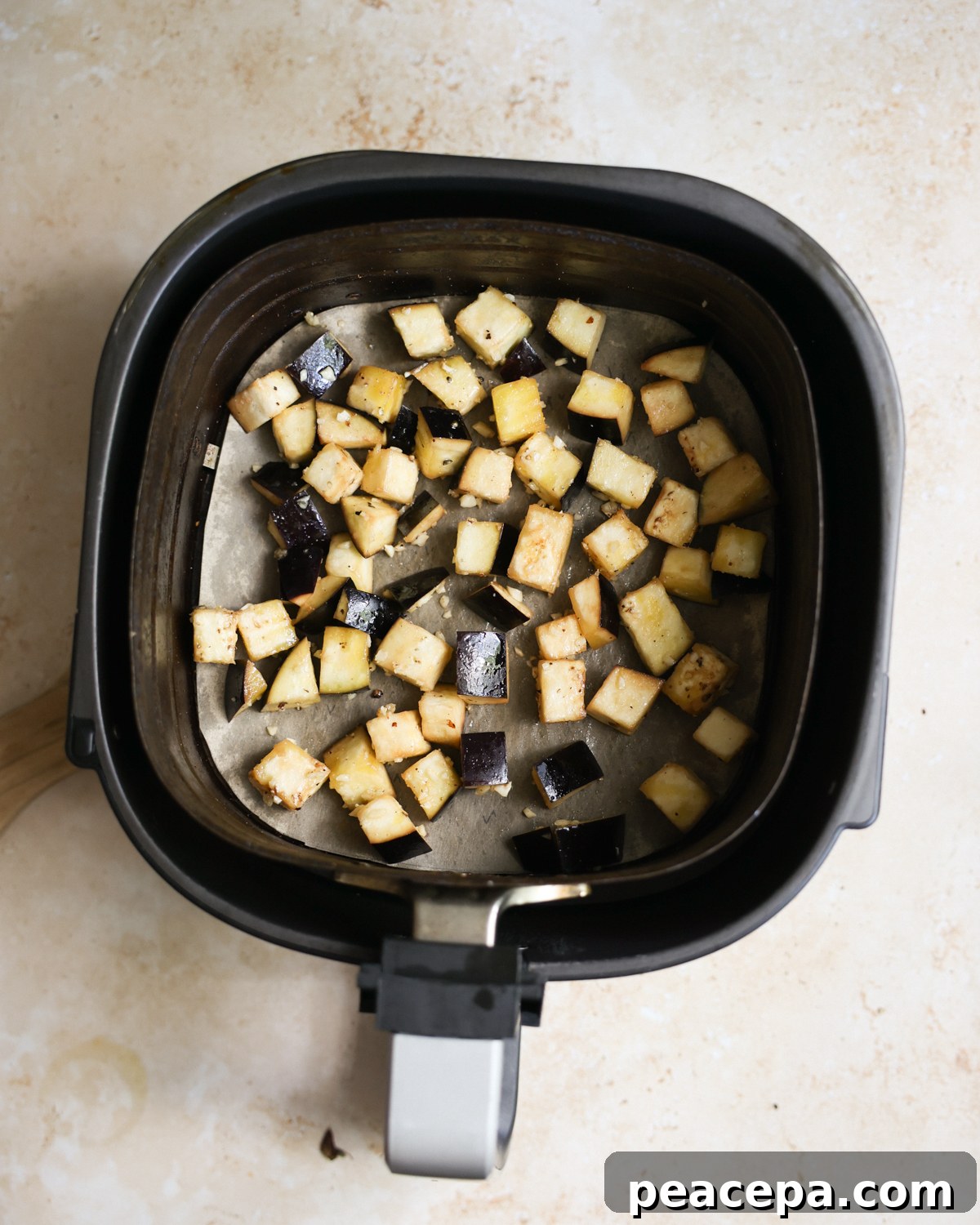 An overhead shot of the eggplant in the air fryer basket before cooking.