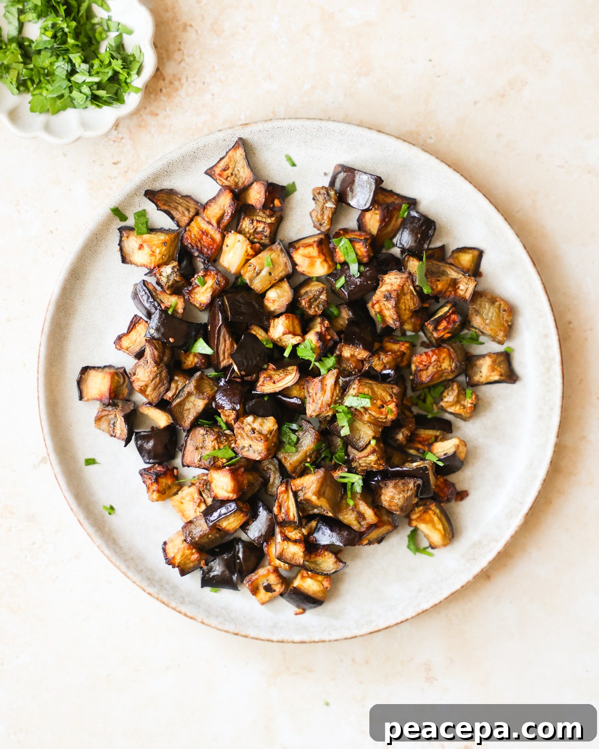 An overhead shot of a plate of air fryer eggplant with chopped herbs.