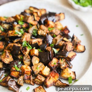 A close-up side shot of a serving plate of air fryer eggplant with chopped herbs.