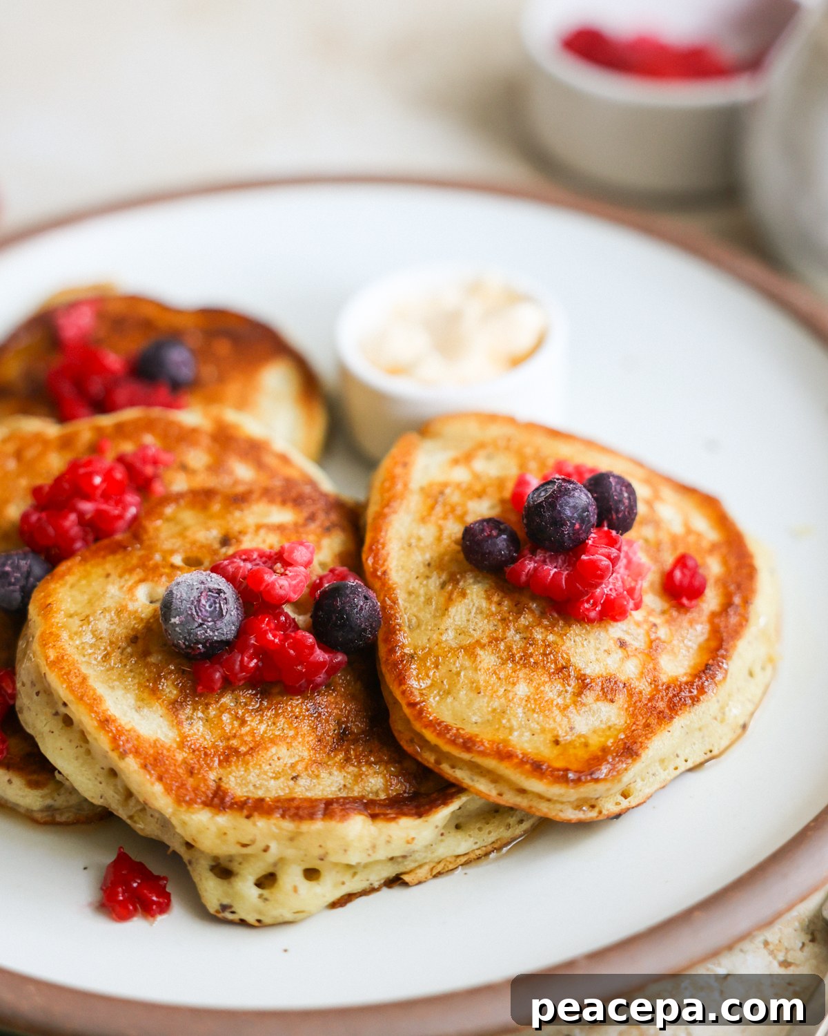 A close-up shot of sourdough discard pancakes on a plate with berries on top.