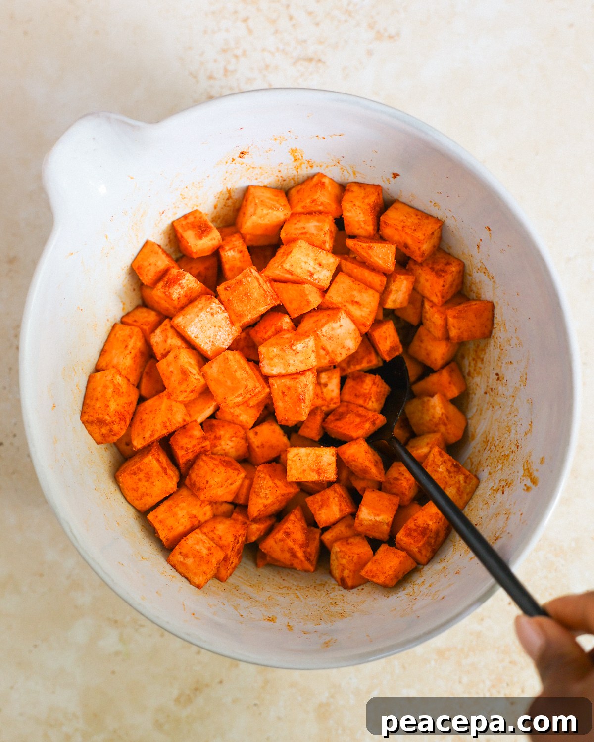 Tossing sweet potatoes in spices.