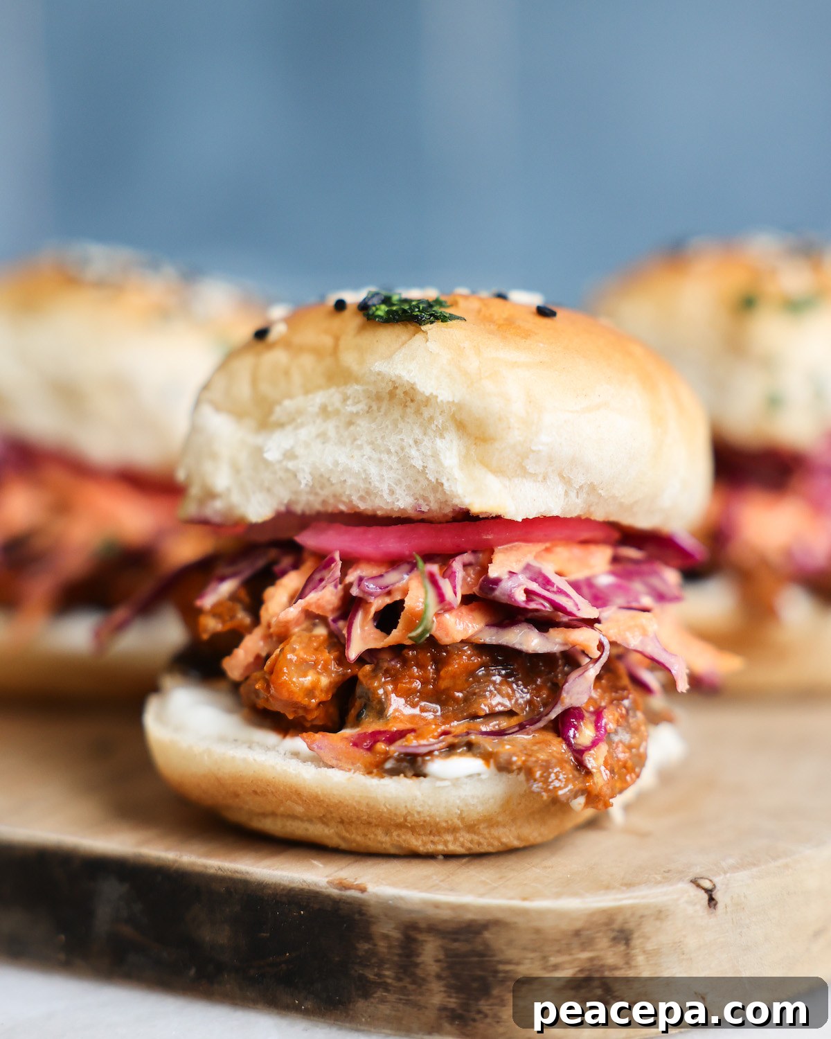 A side shot of mushroom veggie sliders on a wooden cutting board.
