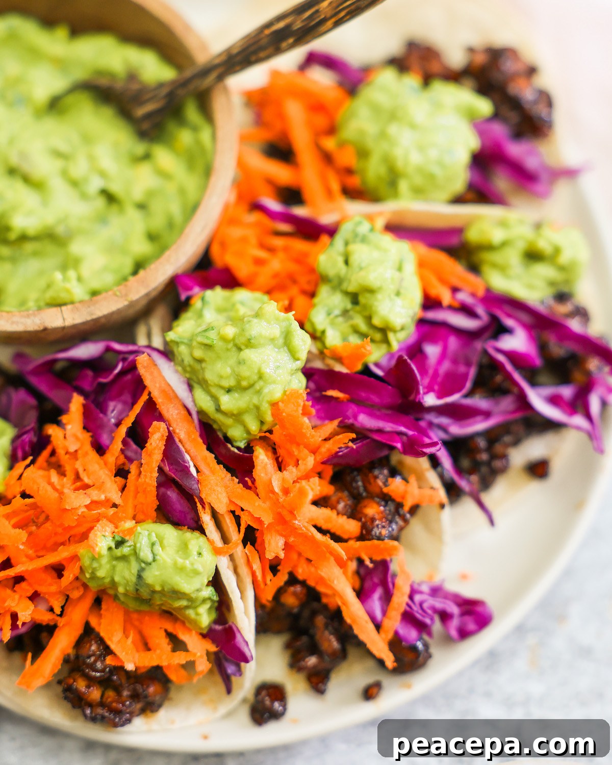 tempeh tacos topped with shredded carrots and cabbage and guacamole