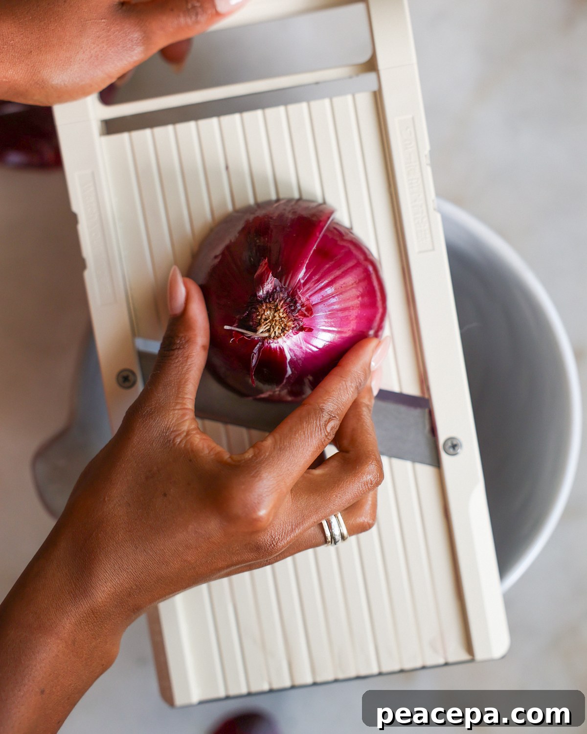 slicing an onion on a mandoline