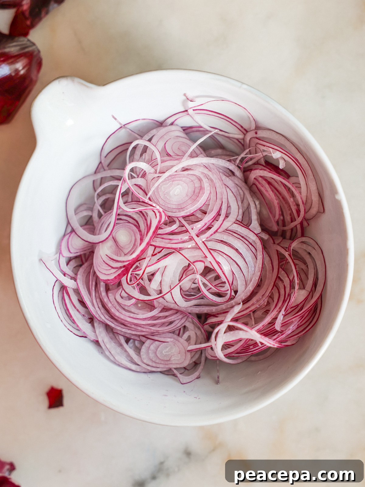 sliced red onions in a mixing bowl