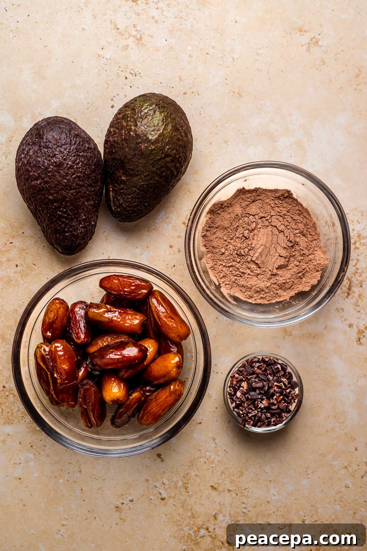 All of the ingredients to make vegan chocolate mouse: avocados, dates, cacao powder, and carob chips.