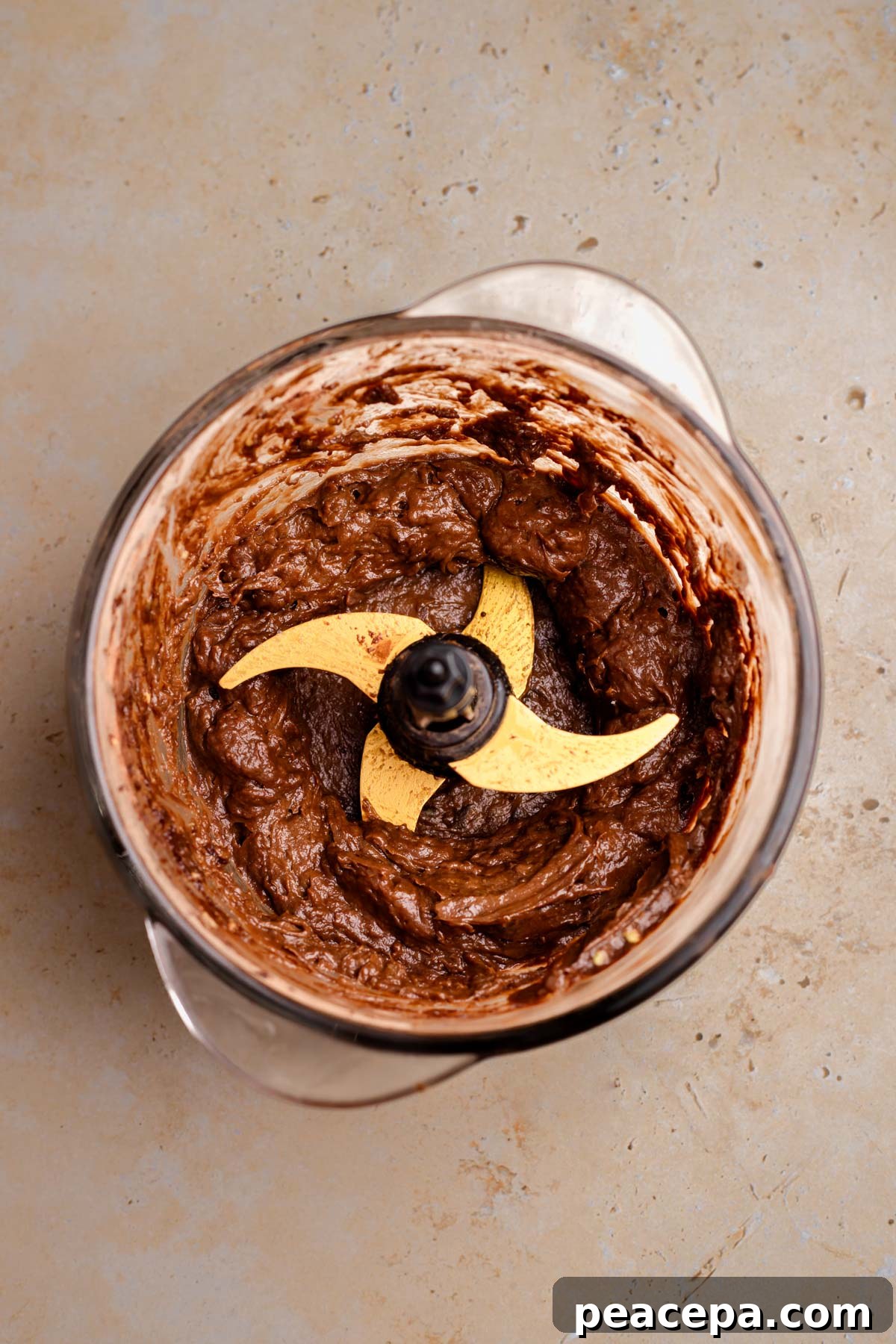 An overhead shot of the vegan chocolate mousse in the bowl of a food processor.