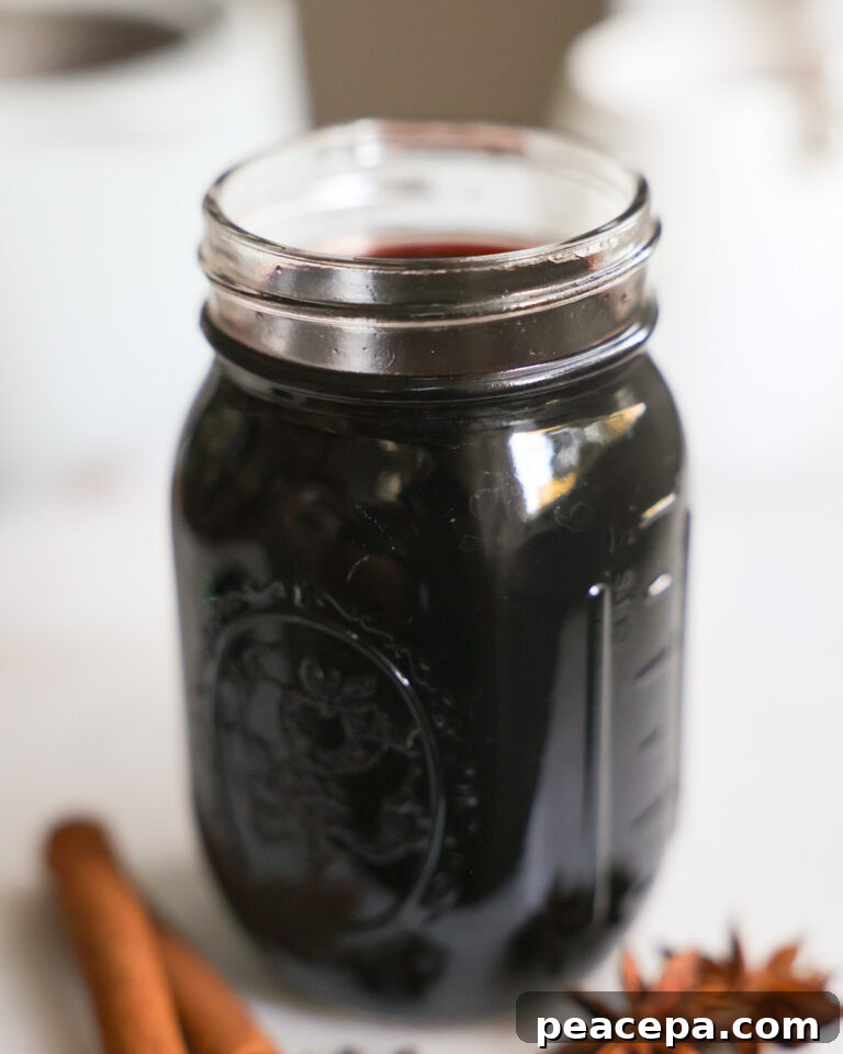 Glass jar filled with Homemade Elderberry Syrup.