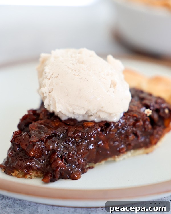 Slice of Vegan Chocolate Pecan Pie on a plate topped with ice cream.