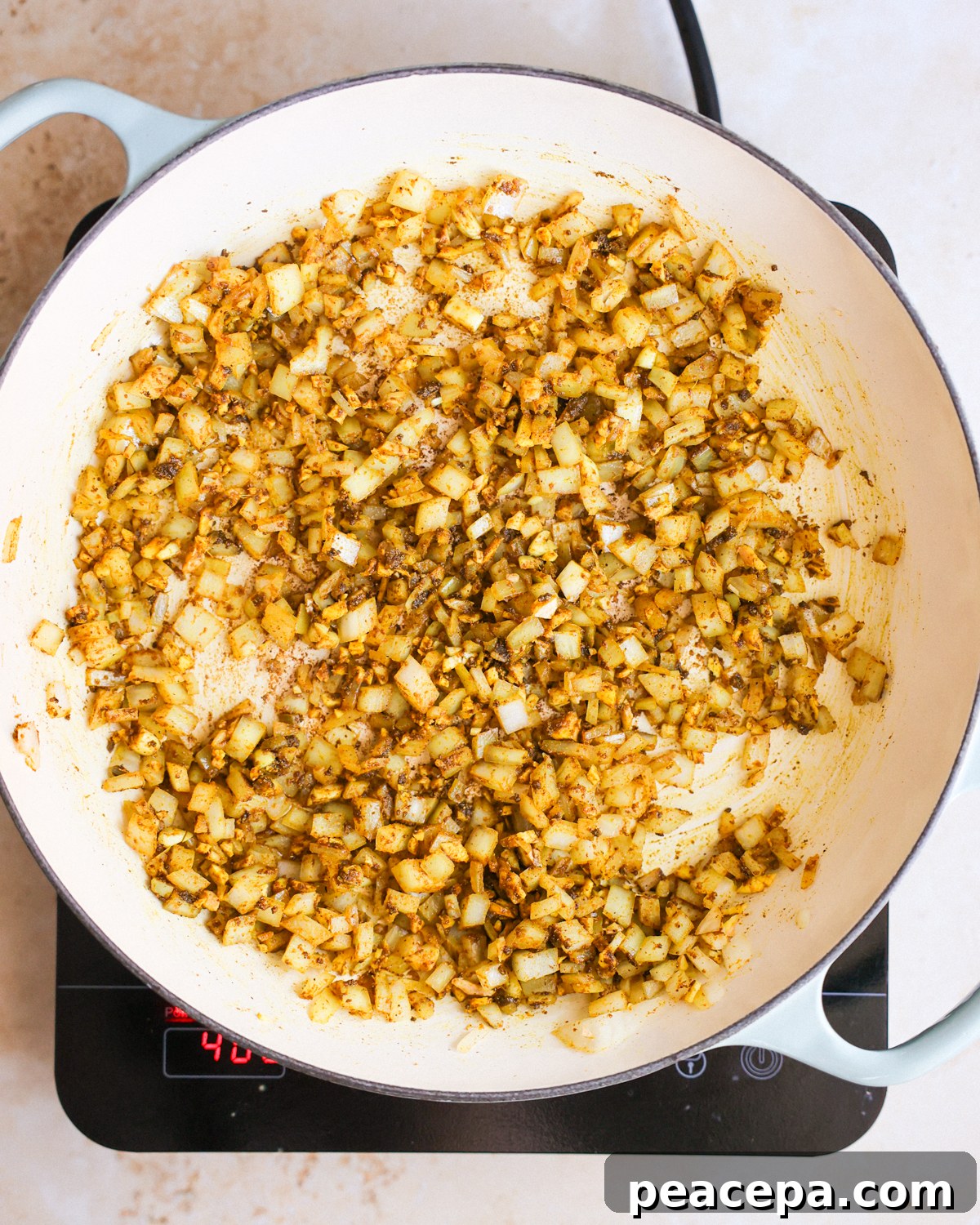 A pan of aromatics (garlic, ginger, and onions) cooked in the Jamaican curry powder and oil.
