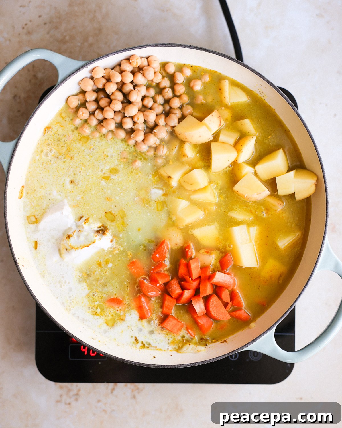 An overhead shot of a white pot of the Jamaican chickpea curry ingredients in the pot before bringing to a simmer.