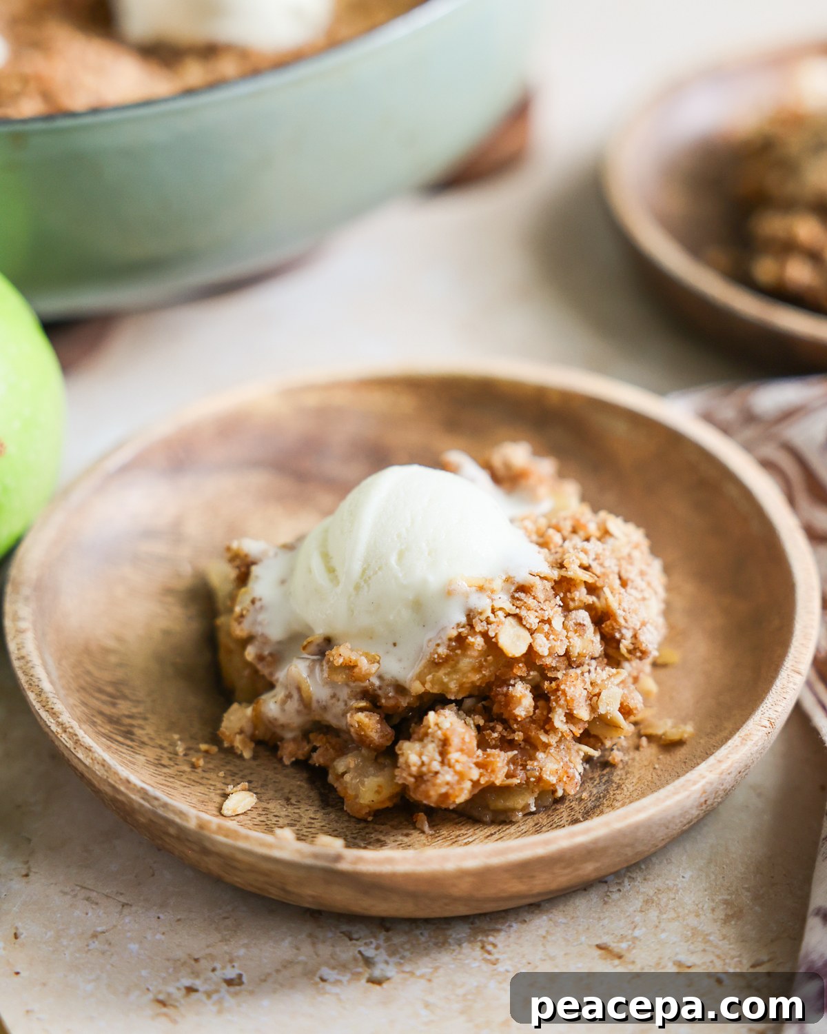 Scoop of apple crisp on a plate and topped with ice cream. 