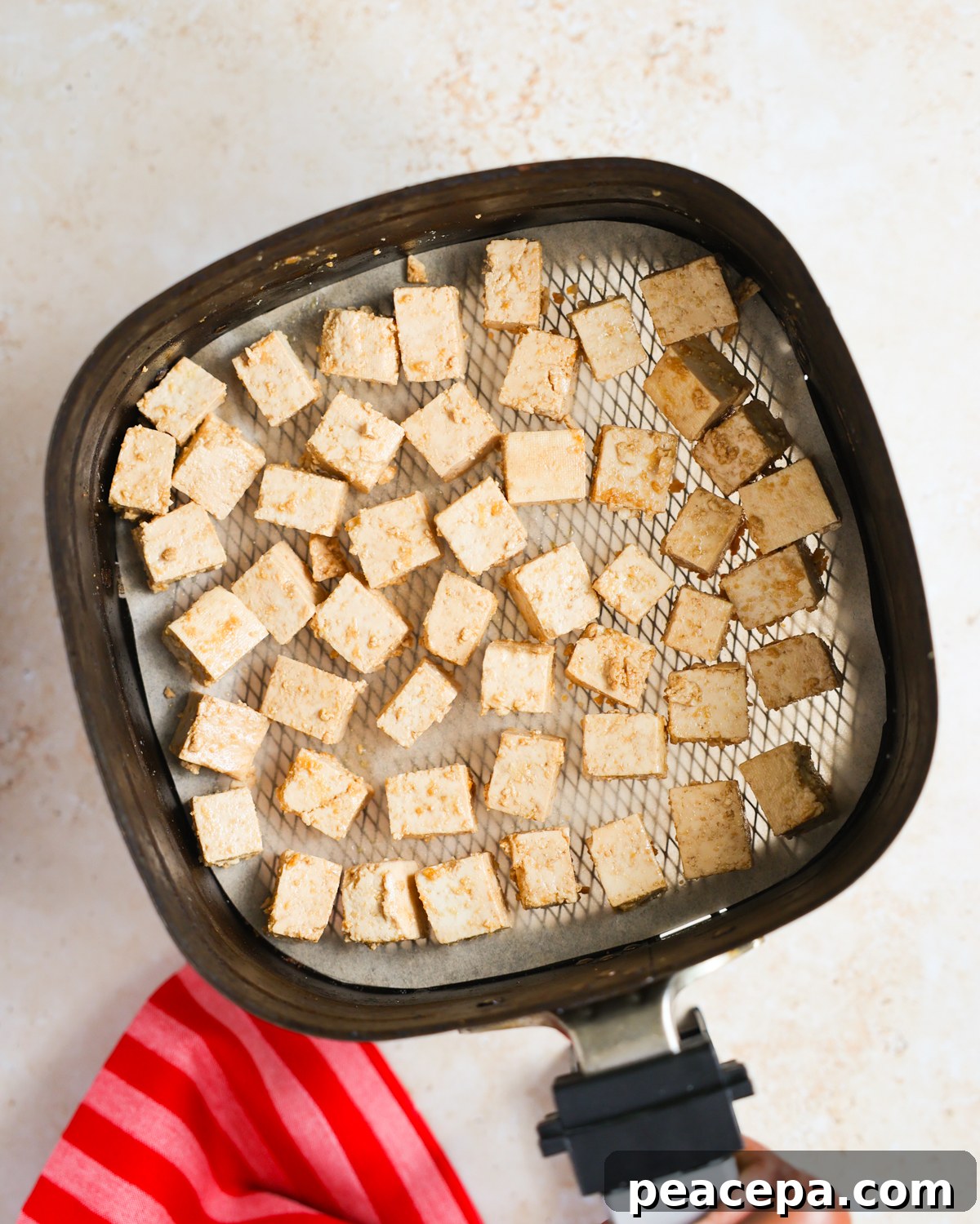 Seasoned tofu in air fryer basket.
