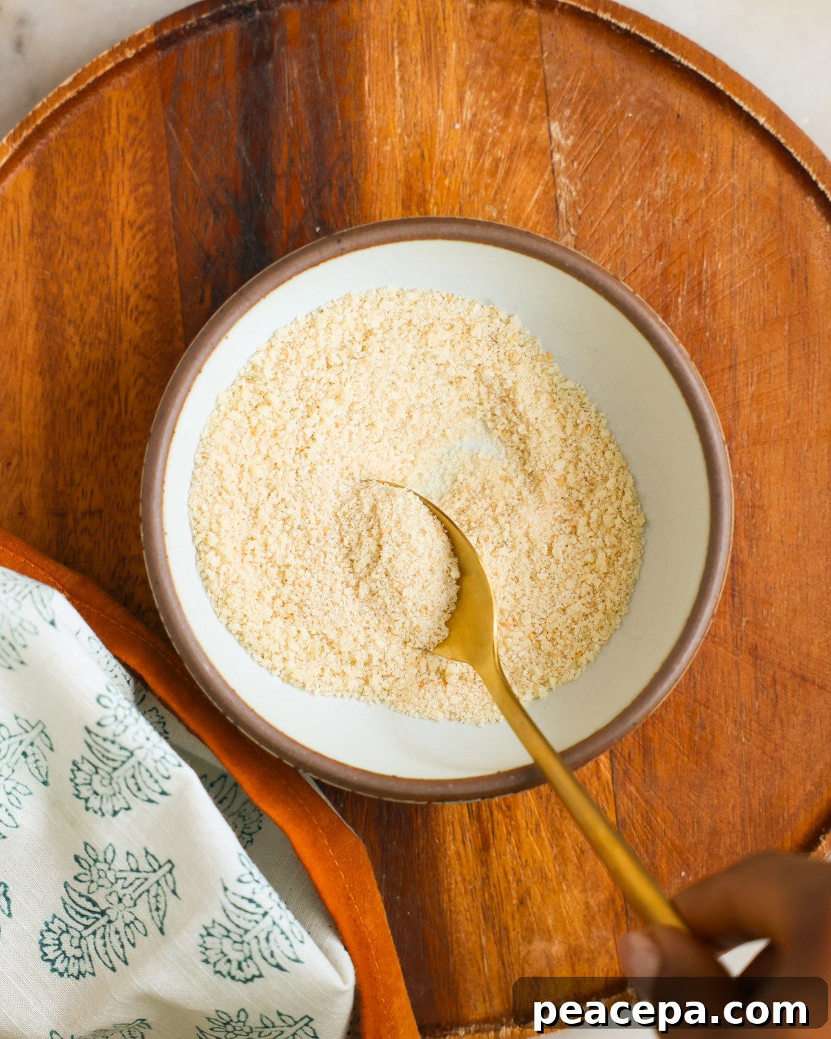 A spoon mixing panko crumbs in a bowl.
