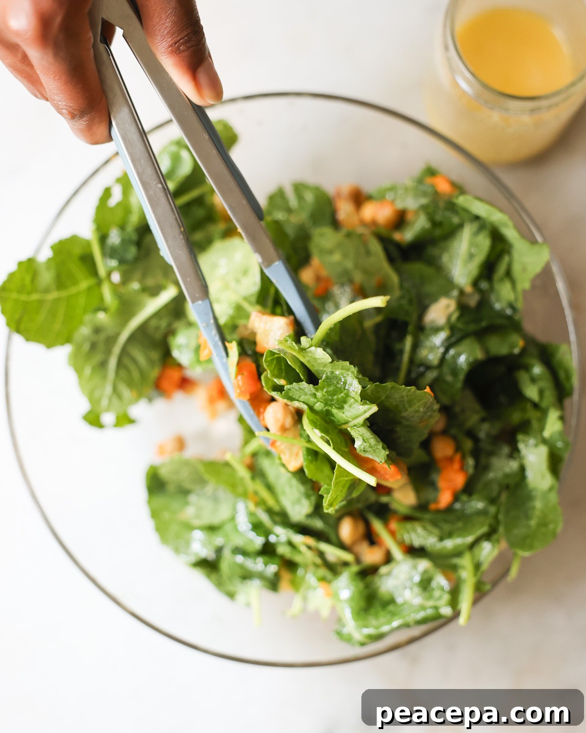 tossing baby kale salad in salad bowl