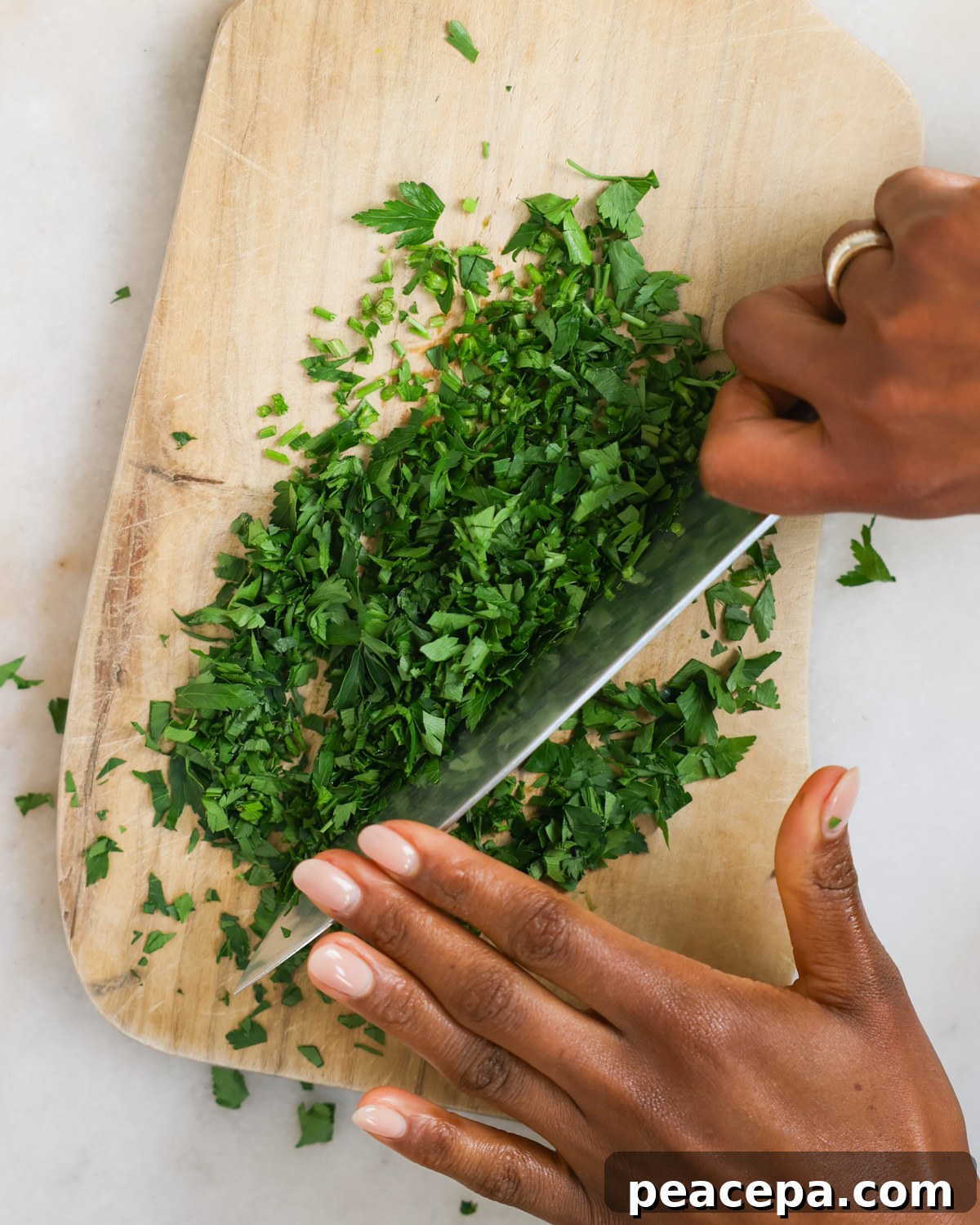 Mincing parsley on a wooden cutting board.
