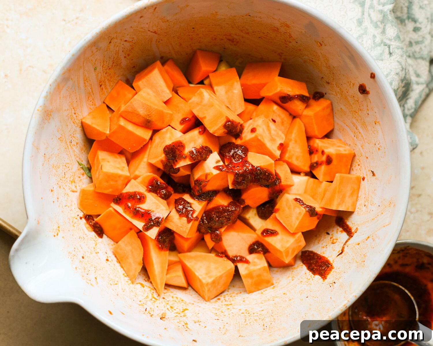Sweet potatoes coated with spices in a bowl.